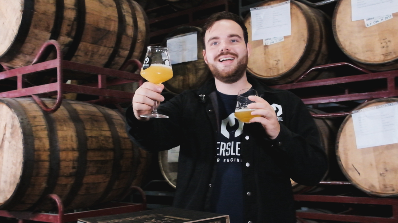 Craft brewer with IPA glass in front of oak barrels