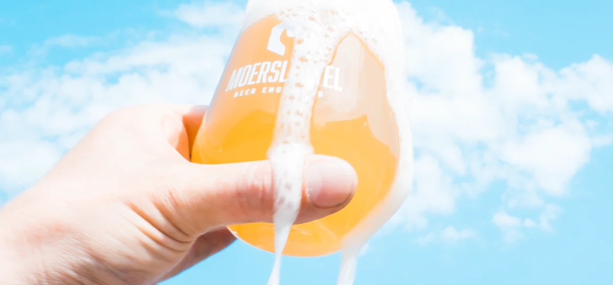 Hazy NEIPA in branded glass with thick foam and citrus aroma