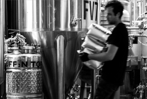 Brewer carrying bags of hops in brewery