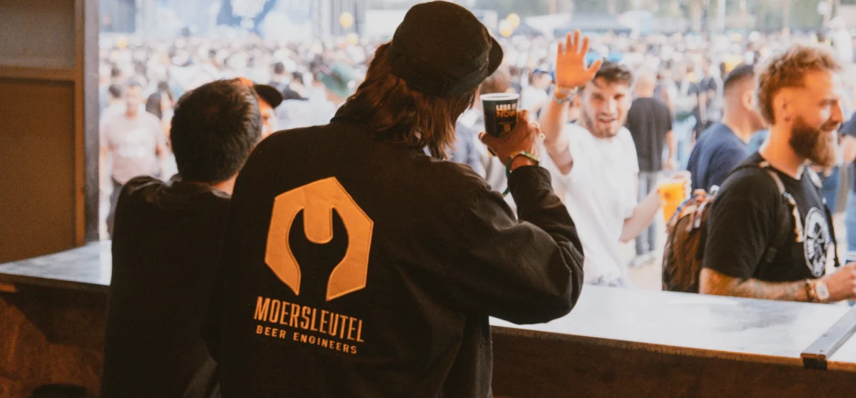 Two people of Moersleutel Craft Brewery cheers with their beers to people at V and B Fest in France